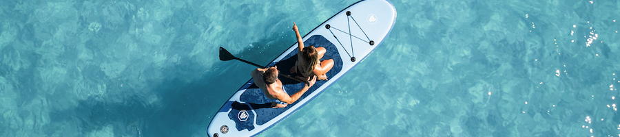 A drone shot of two people on a paddle board in clear water