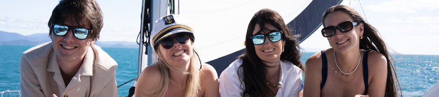 Four people smiling at the camera while lying on a catamaran