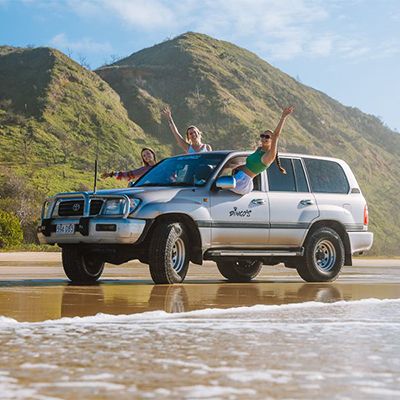 travellers in a 4wd on the beach of kgari