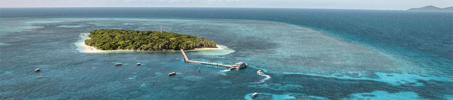 green island surrounded by coral reefs and ocean