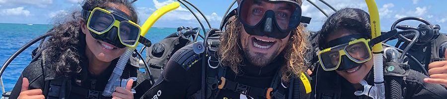 group of scuba divers smiling on a boat at sea