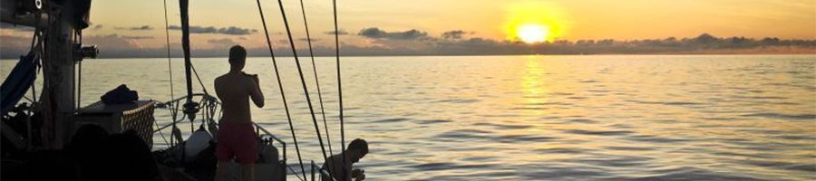 people on a sailboat at sea watching the sunrise