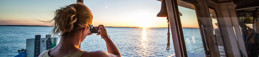 girl on a kgari ferry taking photos of the sunrise