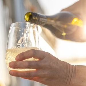 A sailing crew member pouring a guest a glass of white wine