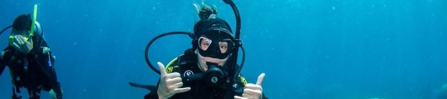 A woman posing for a photo underwater wearing scuba diving gear