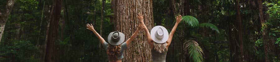 two girls posing in front of a large tree on kgari fraser island