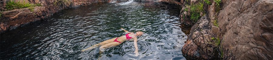 girl floating in a natural rock hole in litchfield national park