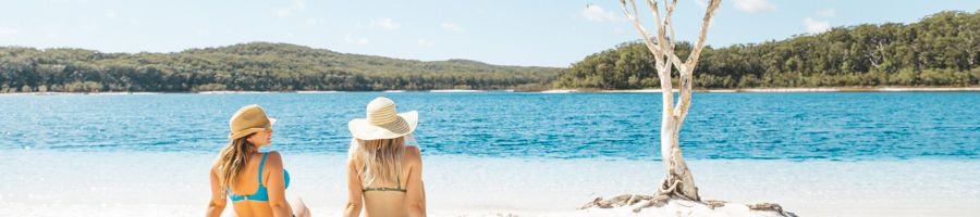 two girls sitting in front of lake mckenzie on kgari