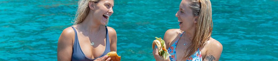girls eating sandwiches on a boat on the water