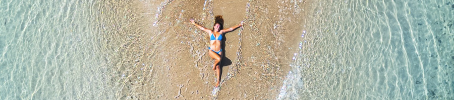 A drone shot of a girl laying in the sand 